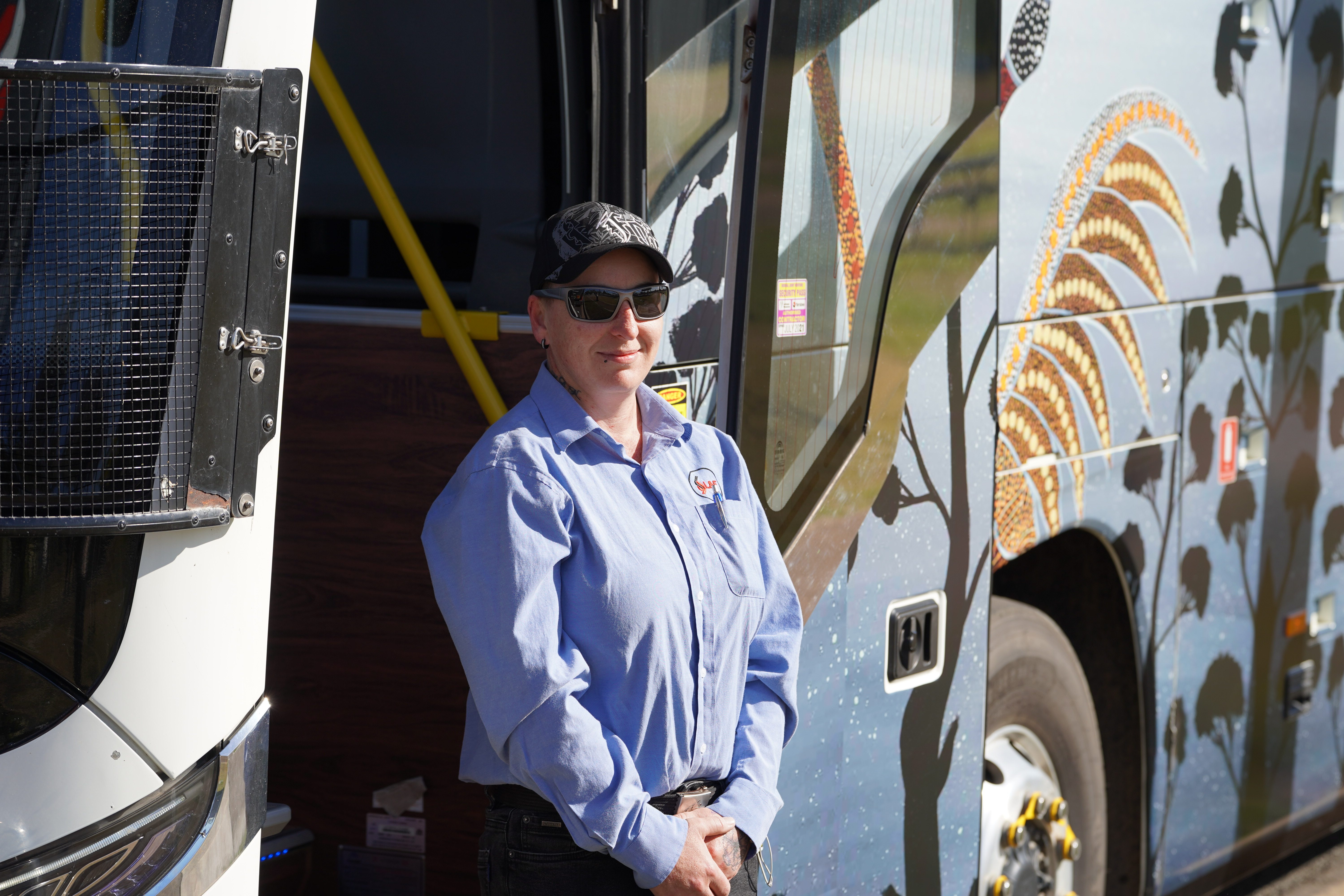 A bus driver waits to welcome on passengers to the  L&F Transfers bus wrapped in an Aboriginal artist's artwork.
