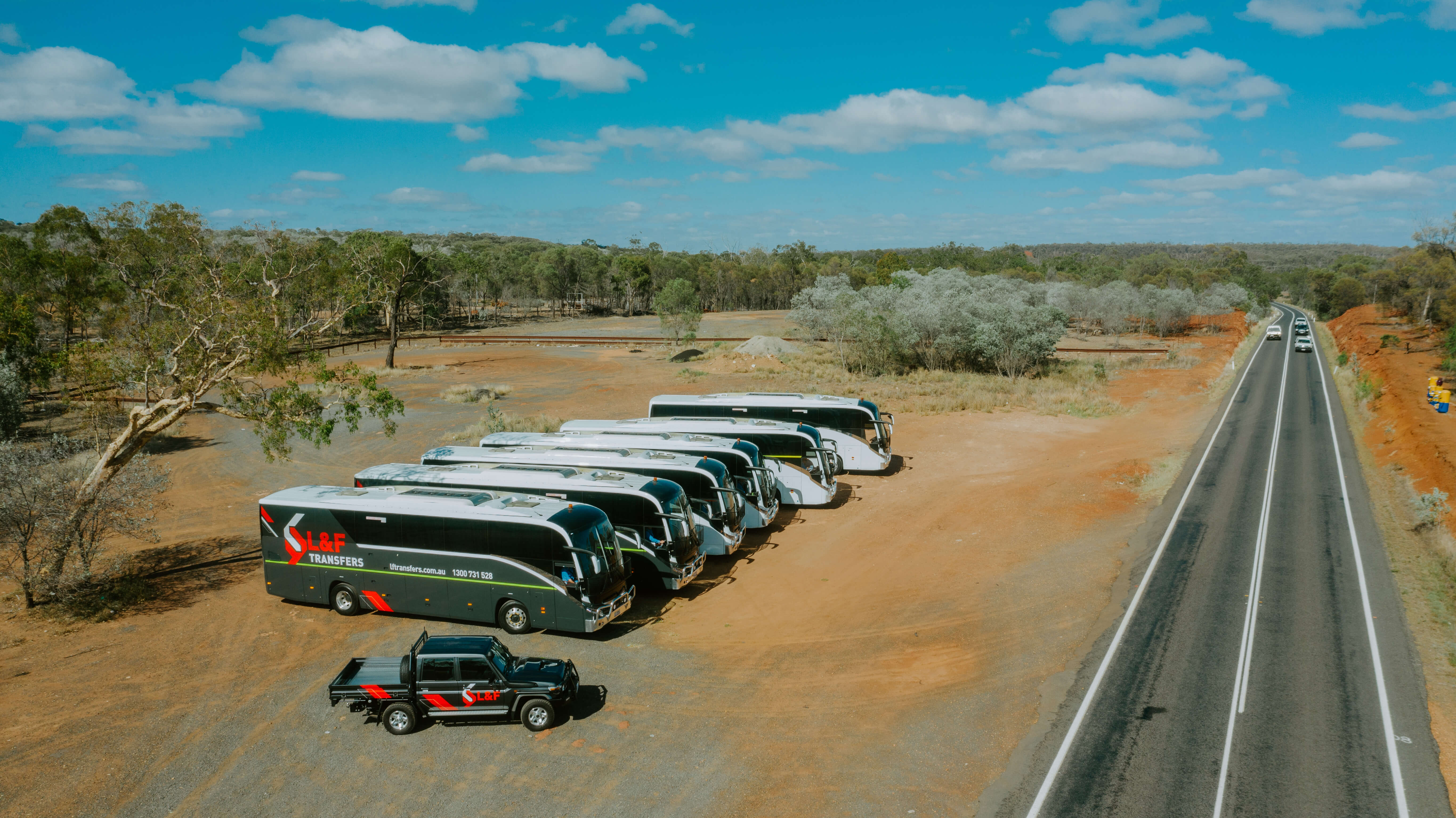 Our luxury coaches parked beside the Capricorn Highway with one or our Fleet Hire utes.